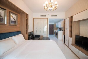 A hotel room with a large bed, a TV, a desk, and a wardrobe.