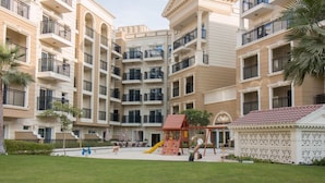 A multi-story residential building with balconies, a children's play area, and a small garden.