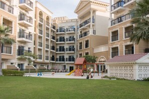 A multi-story residential building with balconies, a children's play area, and a small garden.