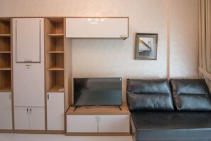 A compact living space with a TV, a sofa, and built-in storage units.