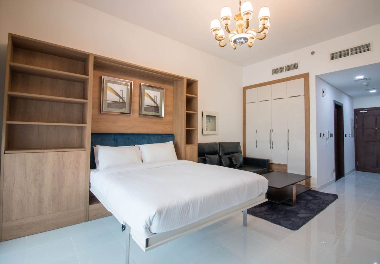 A modern bedroom with a bed, built-in shelving, a desk, and a wardrobe.