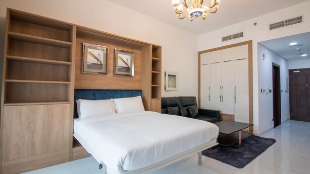 A modern bedroom with a bed, built-in shelving, a desk, and a wardrobe.