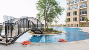 Ein Schwimmbad mit einer Brücke, Rettungsringen und einem Gebäude mit Balkonen.