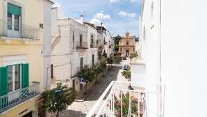 Une rue étroite, bordée de bâtiments des deux côtés, une église visible au loin et un ciel bleu dégagé.
