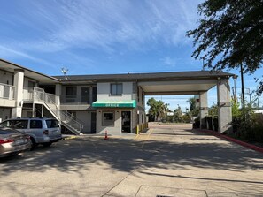 A building with a green awning labeled 'OFFICE' and a covered parking area. - LUXURY INN (Houston)