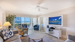 Un salon avec un téléviseur, un canapé, un fauteuil et une vue sur la plage.