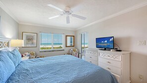 Ein Schlafzimmer mit Bett, Deckenventilator, Fernseher und Kommode.