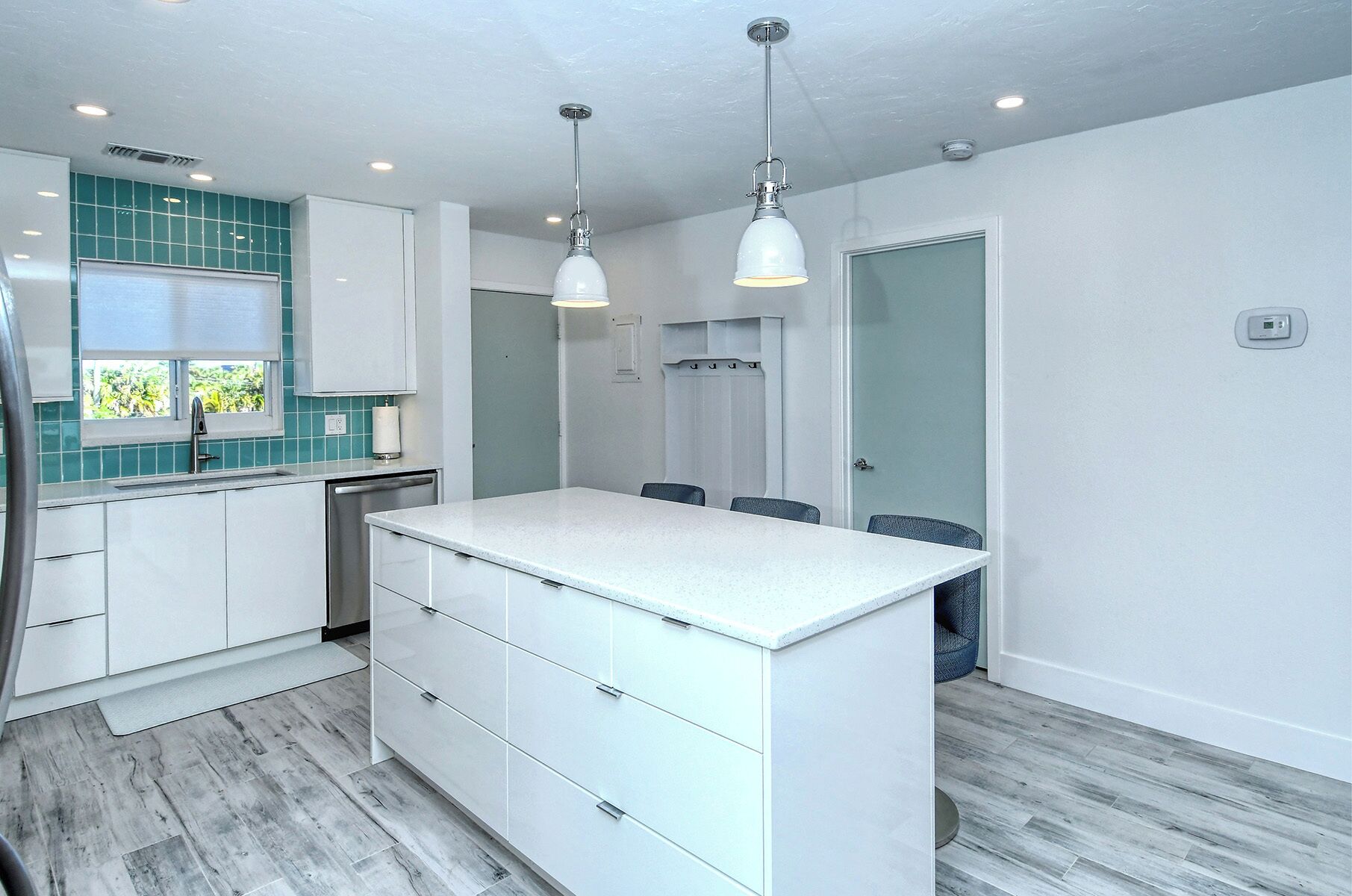 A modern kitchen with white cabinetry, a central island, and a window with a view.