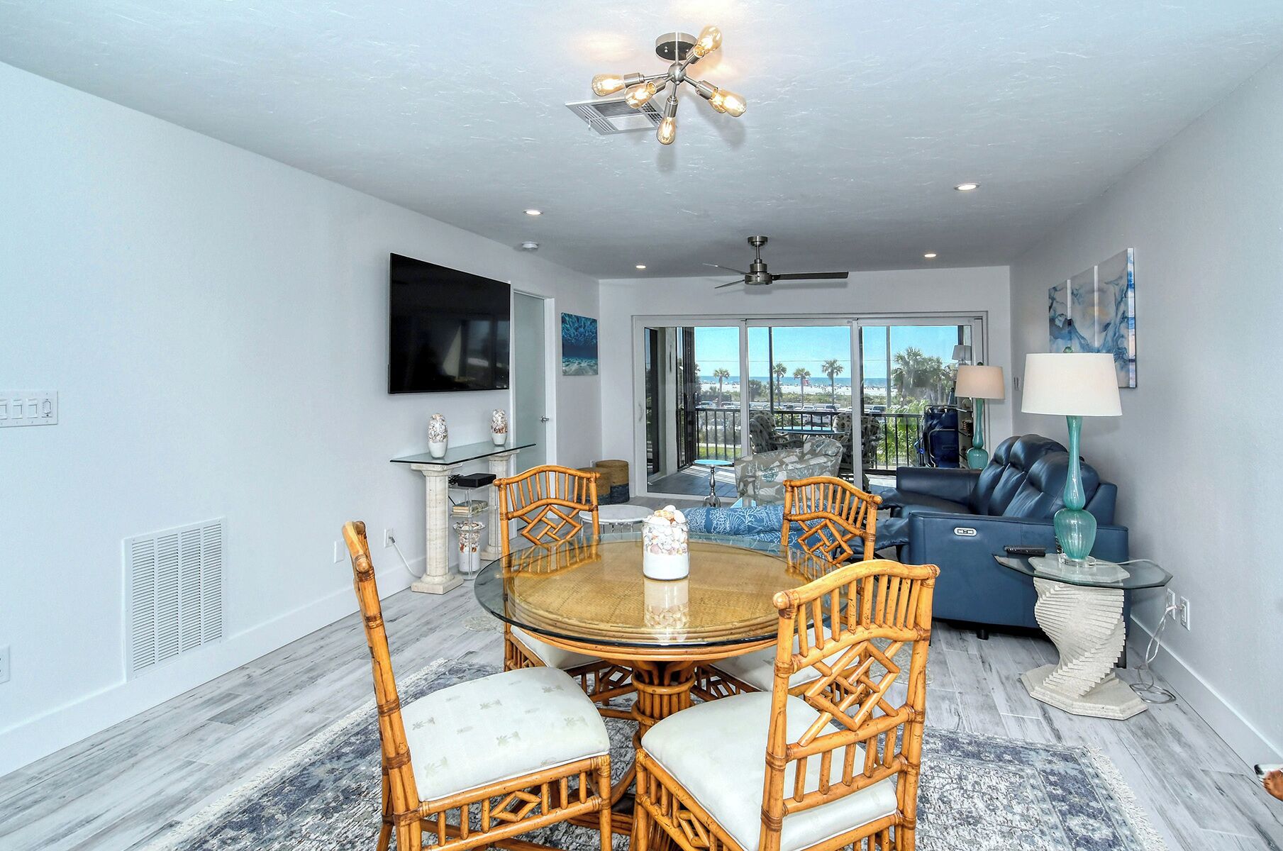 A dining area with a round table, wicker chairs, and a ceiling fan.