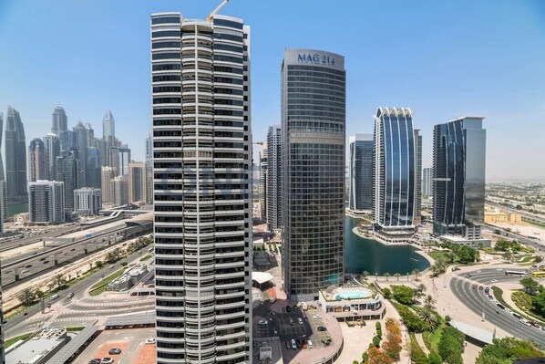 Un edificio de gran altura con fachada curva, una estructura moderna de vidrio y una fuente de agua visible.
