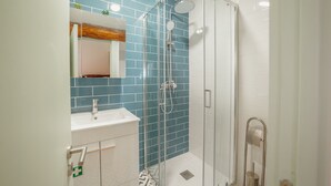 Une salle de bain moderne avec une douche à parois de verre, un lavabo blanc et un miroir au-dessus.
