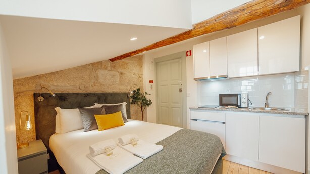 Une chambre comprenant un lit, une table de chevet et une petite kitchenette équipée d’un four à micro-ondes et d’un évier.