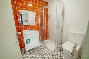 Un baño con ducha, inodoro, lavabo y espejo.