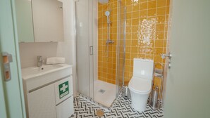 Une salle de bain équipée d’une douche, de toilettes, d’un lavabo et d’un panneau indiquant le matériel de premiers secours.
