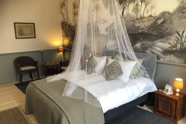 Comfortable king sized bed with mosquito net and side tables