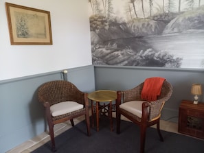 A corner room with two wicker chairs, a small round table, and a large wall mural depicting a waterfall. - Le Jardin des Bosquets B&B / chambre d'hote (Auchay-sur-Vendée)
