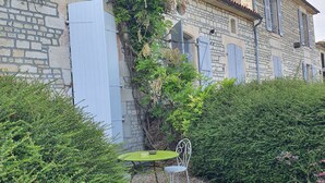 Ein Steinhaus mit Garten, inklusive Tisch und Stuhl.