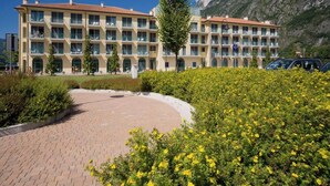 Un hotel con varios balcones, un patio empedrado y montañas al fondo.
