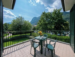 A balcony with a table set for two, chairs, and a vase of flowers.