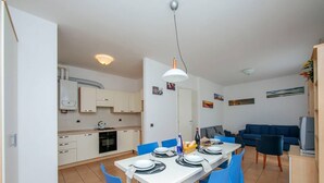 A modern apartment with a dining area, kitchen, and living space.