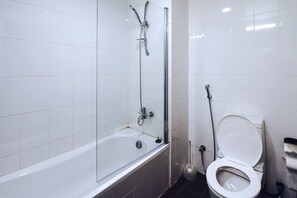 A bathroom with a glass-enclosed shower, a toilet, and a plunger.
