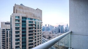 Un immeuble de grande hauteur orné d’une enseigne « EMAAR », doté d’un balcon en verre et offrant une vue sur le paysage urbain.