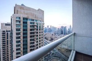 Un immeuble de grande hauteur orné d’une enseigne « EMAAR », doté d’un balcon en verre et offrant une vue sur le paysage urbain.