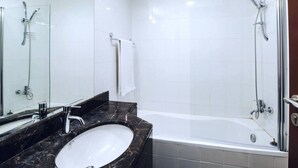 Une salle de bain avec un lavabo en marbre, une baignoire et une douche à parois de verre.