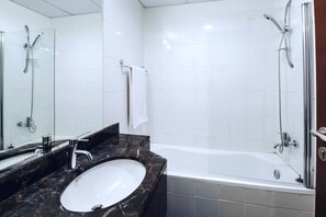 A bathroom with a marble sink, a bathtub, and a glass-enclosed shower.