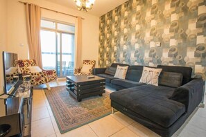 A living room with a sofa set, a coffee table, a TV, and a patterned wall.