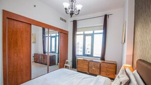 A bedroom with a bed, a dresser, a mirror, and a window with curtains.