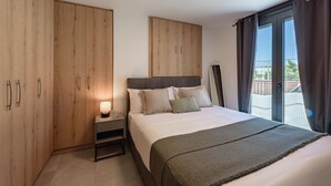 Un dormitorio con cama, mesita de noche, armario de madera y vistas al exterior.