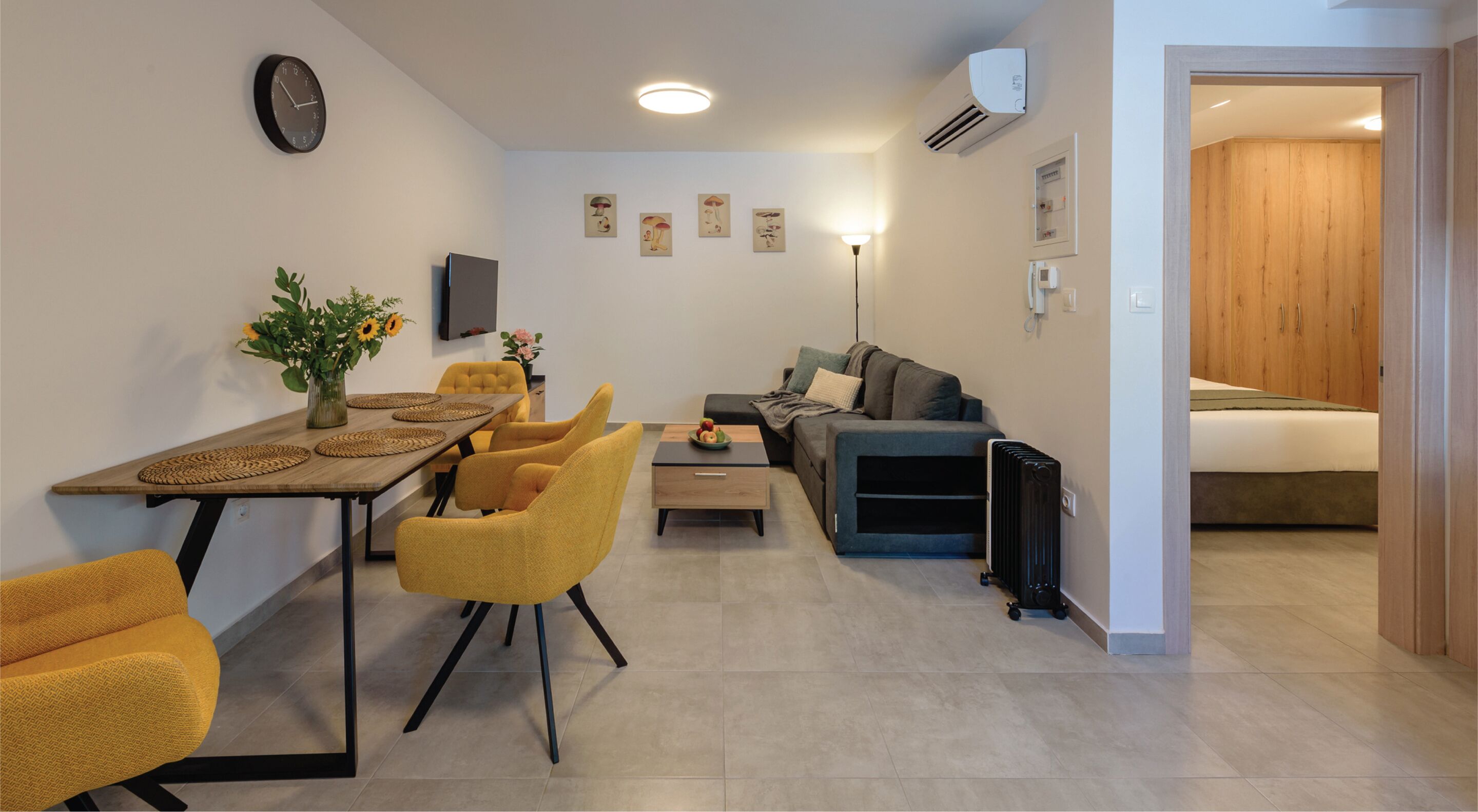 A modern living room with a dining area, a sofa, a coffee table, and a radiator.