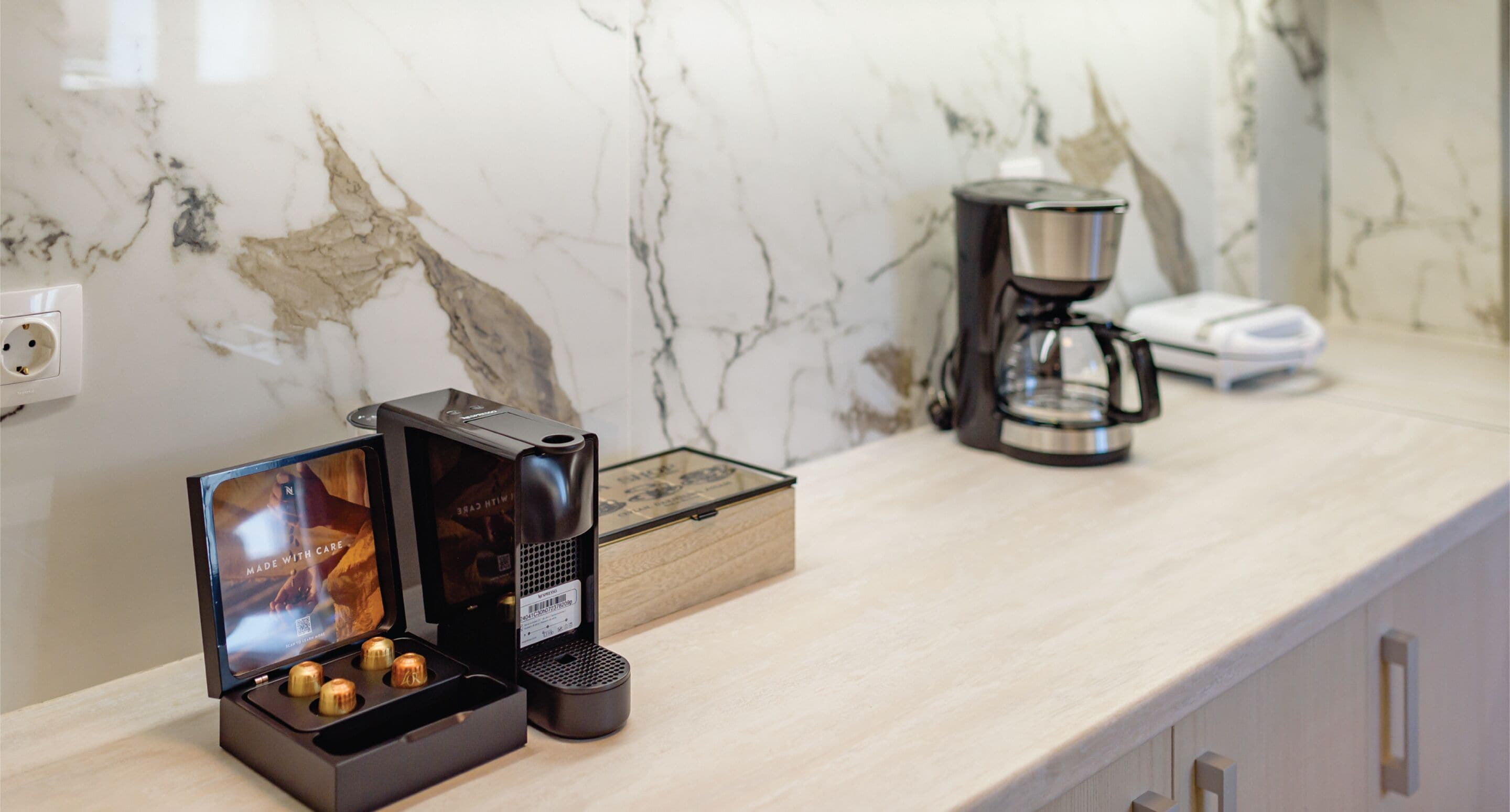 Una encimera de cocina con una cafetera, una caja y una presentación de bombones.
