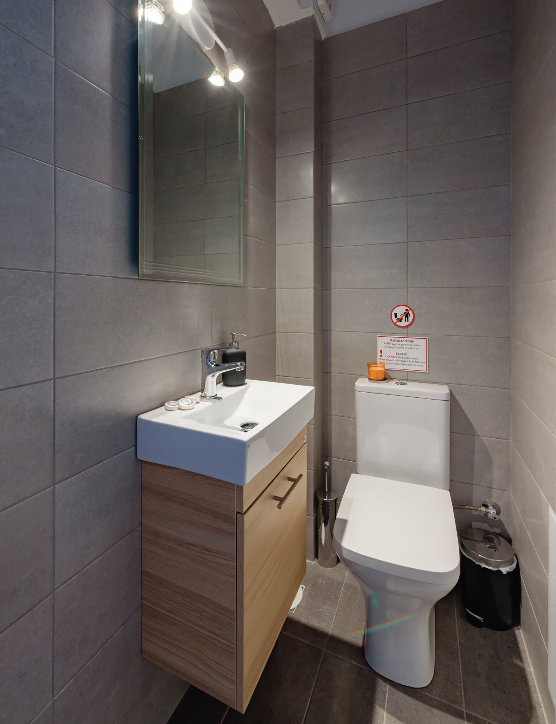 A modern bathroom with a white sink, wooden vanity, and a toilet.