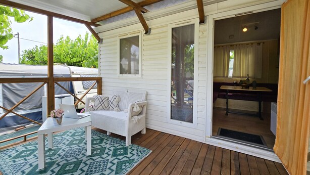 A covered porch with a white sofa, a small table, and a patterned rug. - Maia: Family bungalow (Canet de Mar)