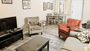 A living room with a TV, two armchairs, a sofa, a coffee table, and a dining area with chairs and a table. - 2 Br 2 b Condo at Unv of Notre Dame Short and Long Term Stays Welcome ND Football A5 (South Bend)
