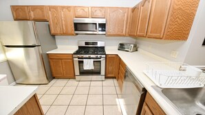 A compact kitchen with wooden cabinets, a stainless steel refrigerator, a microwave, a stove, and a toaster. - 2 Br 2 b Condo at Unv of Notre Dame Short and Long Term Stays Welcome ND Football A5 (South Bend)