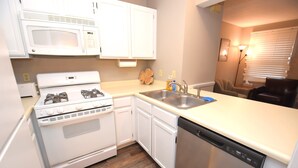 A kitchen with white cabinets, a microwave, stove, dishwasher, and a sink. - Condo at the University of Notre Dame D3 (South Bend)