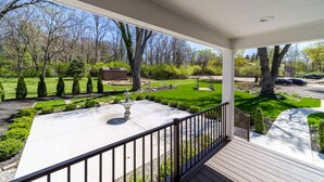 A covered porch with a view of a well-maintained garden and trees. - Modern Home Just 10 Mins to Notre Dame 18384 (South Bend)