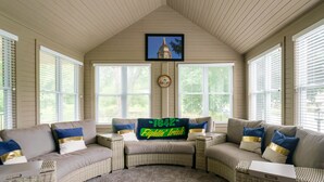 A cozy room with a curved sofa set, a fan cave sign, and a framed picture of a building on the wall. - Modern Home Just 10 Mins to Notre Dame 18384 (South Bend)