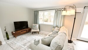Ett vardagsrum med en soffa, en tv och en golvlampa.
