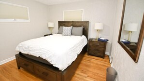 A bedroom with a bed, wooden nightstands, a ceiling fan, and a large mirror. - Remodeled Home 1 Mile From Notre Dame 1150 (South Bend)