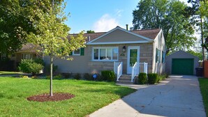 A single-story house with a front porch, a garage, and a well-maintained lawn. - Remodeled Home 1 Mile From Notre Dame 1150 (South Bend)