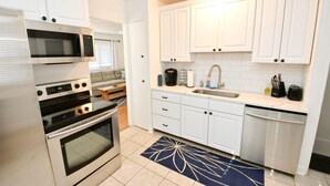 A modern kitchen with white cabinets, stainless steel appliances, and a tiled backsplash. - Remodeled Home 1 Mile From Notre Dame 1150 (South Bend)