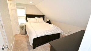 Ein Schlafzimmer mit einem Bett, einem Nachttisch, einem Papierkorb und einer Tür.