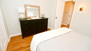 Une chambre à coucher avec un lit, une commode, un miroir et une table de chevet.