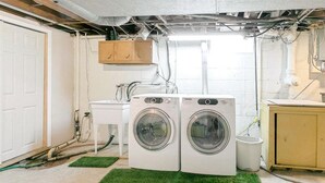 Une buanderie équipée de deux machines à laver à chargement frontal, d’un évier et d’un meuble de rangement.
