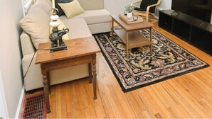 Un salon comprenant un canapé, une table basse, une lampe, un fauteuil, un téléviseur et un tapis à motifs.