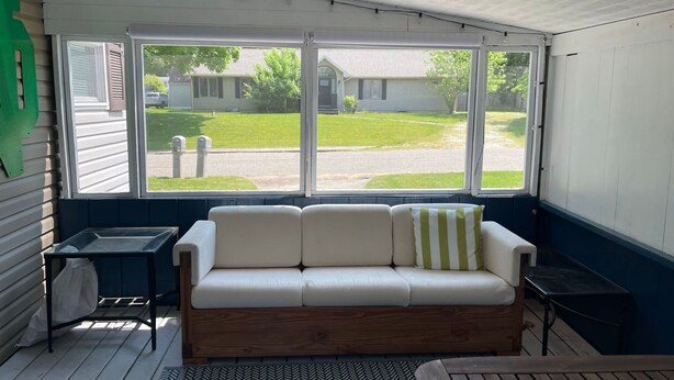 A room with a wooden bench, a white sofa with striped cushions, and a large window offering a view of a residential street. - Extra Entertainment Space Just 7 Blocks to ND Campus 54211 (Mishawaka)